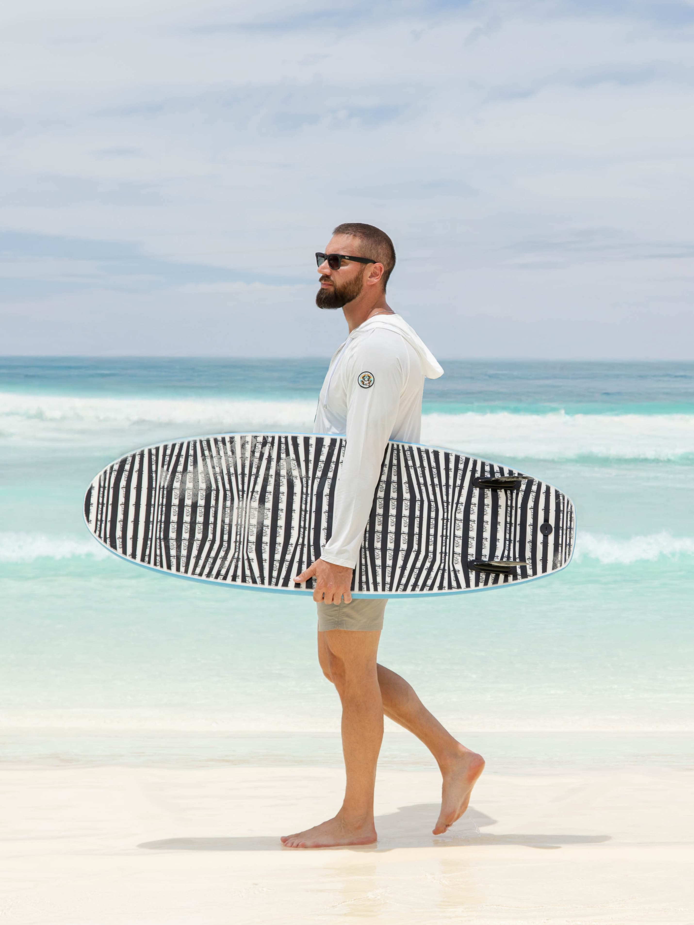 Man walking with surfboard in hoodie
